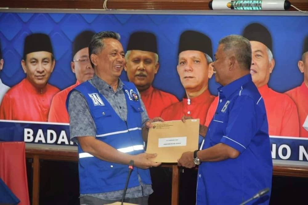 Ahmad (kanan) menyampaikan watikah kepada Ahmad Razif serta 26 calon BN yang lain di Pejabat Badan Perhubungan UMNO Negeri, di sini pada Khamis.