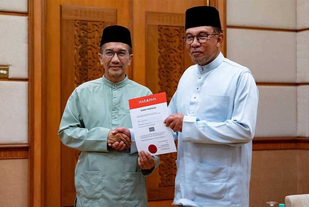 Anwar (kanan) menyampaikan watikah pelantikan kepada calon PRK Parlimen Kuala Terengganu, Azan Ismail di bilik kenamaan Lapangan Terbang Sultan Mahmud di Kuala Nerus pada Jumaat.