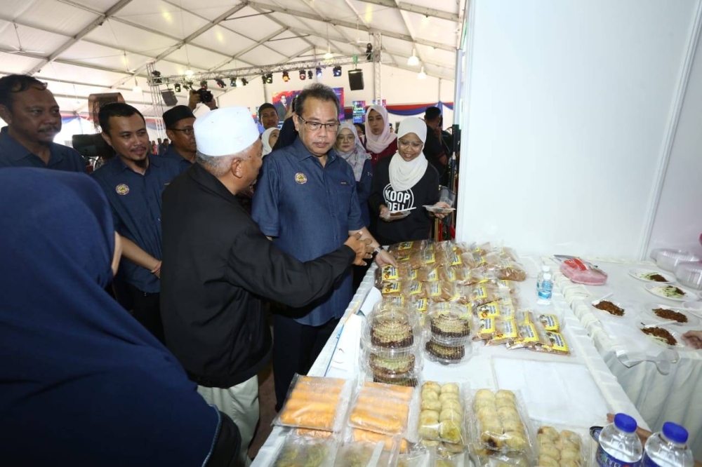 Abdul Fattah (dua dari kanan) meninjau ruang pameran koperasi-koperasi di Perak yang menyertai Karnival 100 tahun KAKIB di Dataran Sultan Azlan Shah, Meru Raya pada Sabtu.