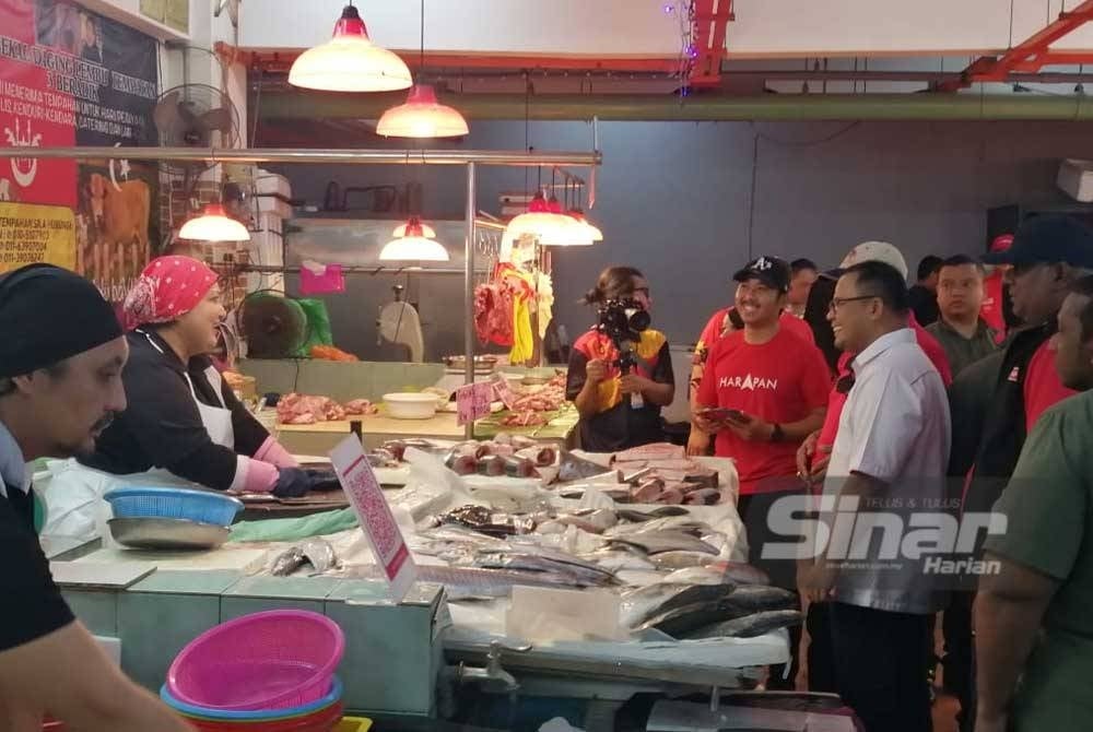 Amirudin (kanan) menyantuni peniaga Pasar Selayang Baru pada Ahad.