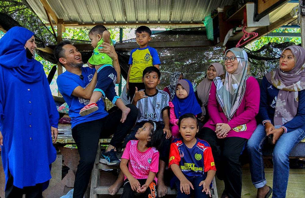 Mohd Najib (dua dari kiri) dan isteri (kiri) bermesra dengan seorang kanak-kanak ketika menyaksikan pertandingan sepak raga tuju.