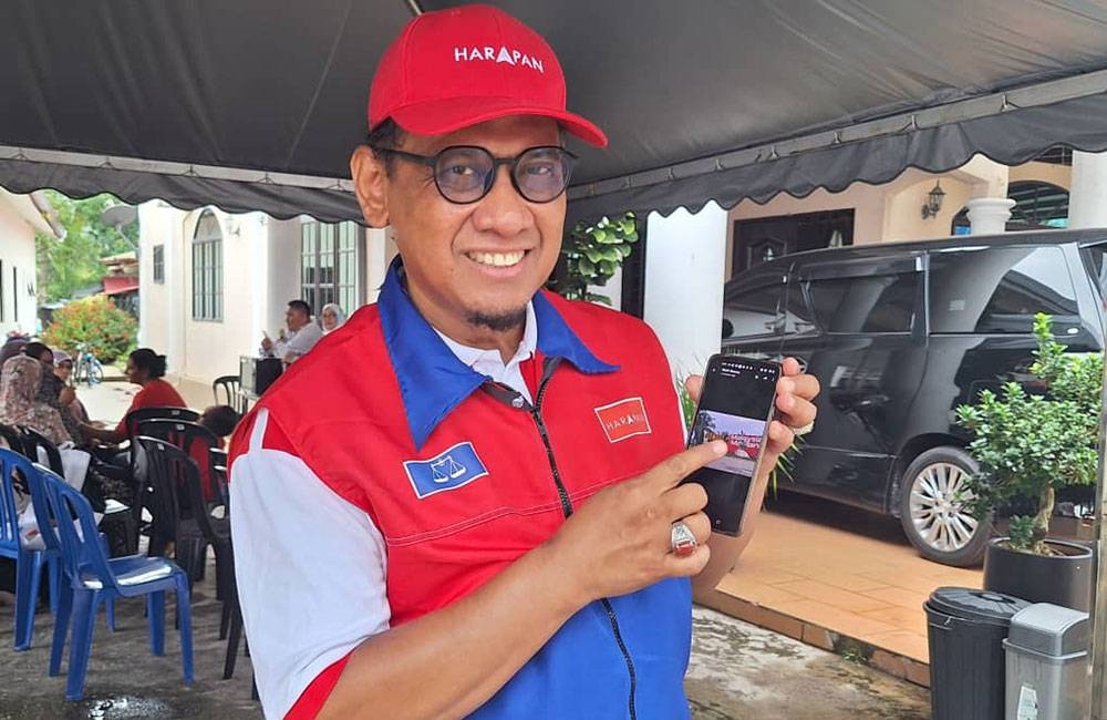 Mohd Yahya menunjukkan kain rentang digantung memaparkan gambar Perdana Menteri, Datuk Seri Anwar Ibrahim dipotong dan dilubangkan pihak tidak bertanggungjawab menerusi telefon bimbitnya.