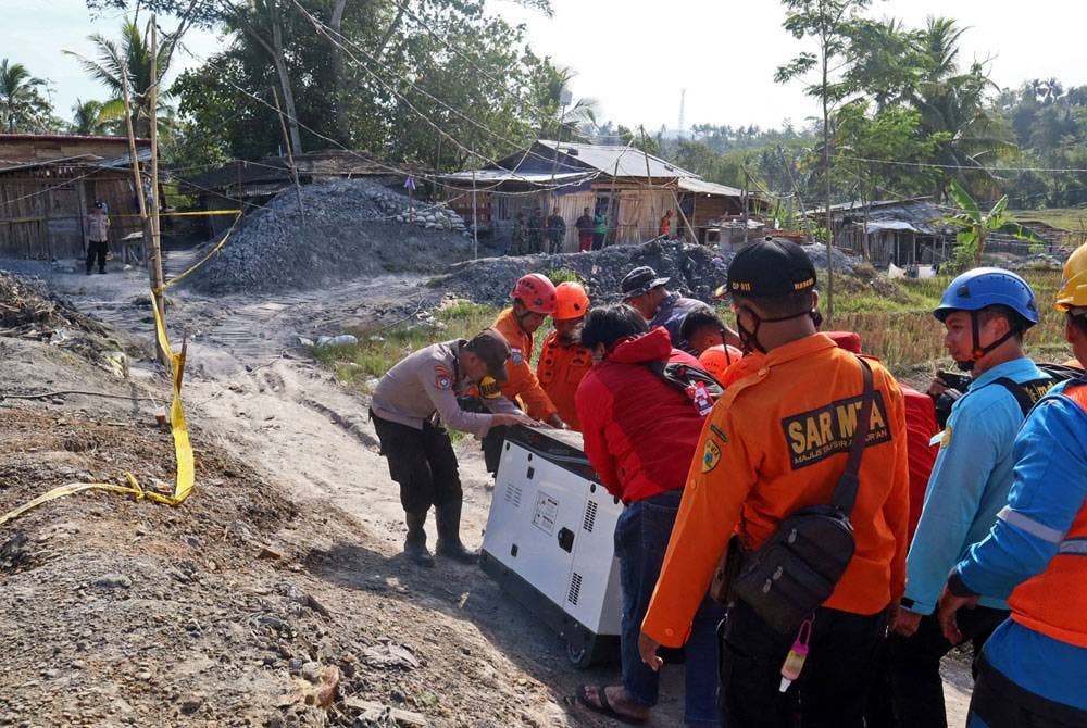 Anggota penyelamat membawa janakuasa semasa operasi mencari pelombong tertimbus di Banyumas. - AFP