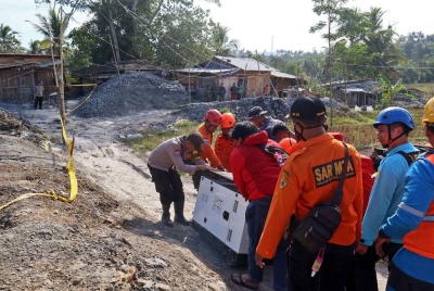 Anggota penyelamat membawa janakuasa semasa operasi mencari pelombong tertimbus di Banyumas. - AFP