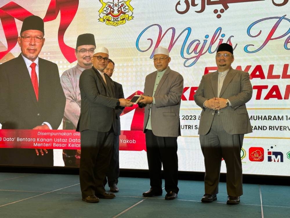 Ahmad (dua dari kanan) menyampaikan alat pembayaran elektronik kepada Dr Mohamad Ramizu (kiri).
