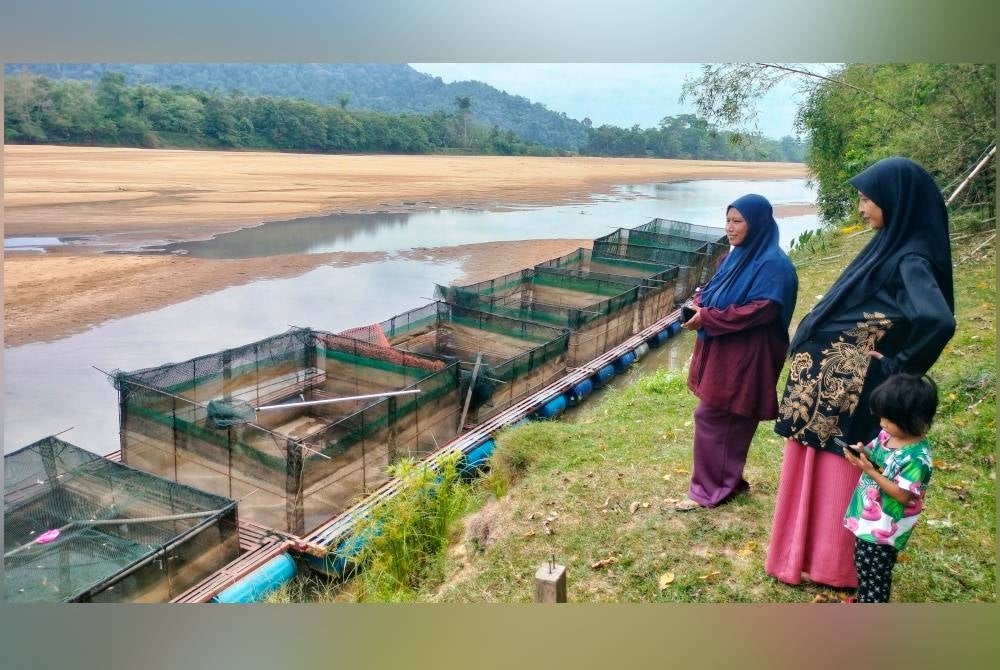 Rosmawati dan Rosmanira melihat suasana air surut dan beting pasir yang timbul di kawasan sangkar ikan yang terjejas pada Selasa.
