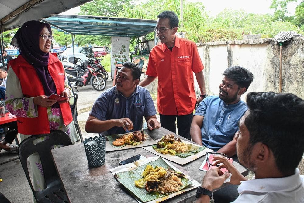 Dr. Zaliha (kiri) membantu calon Pakatan Harapan bagi kerusi Parlimen Kuala Terengganu Azan Ismail (berdiri, tengah) ketika berkempen sempena PRK Parlimen Kuala Terengganu di sebuah warung Bukit Kecil hari ini. - Foto Bernama