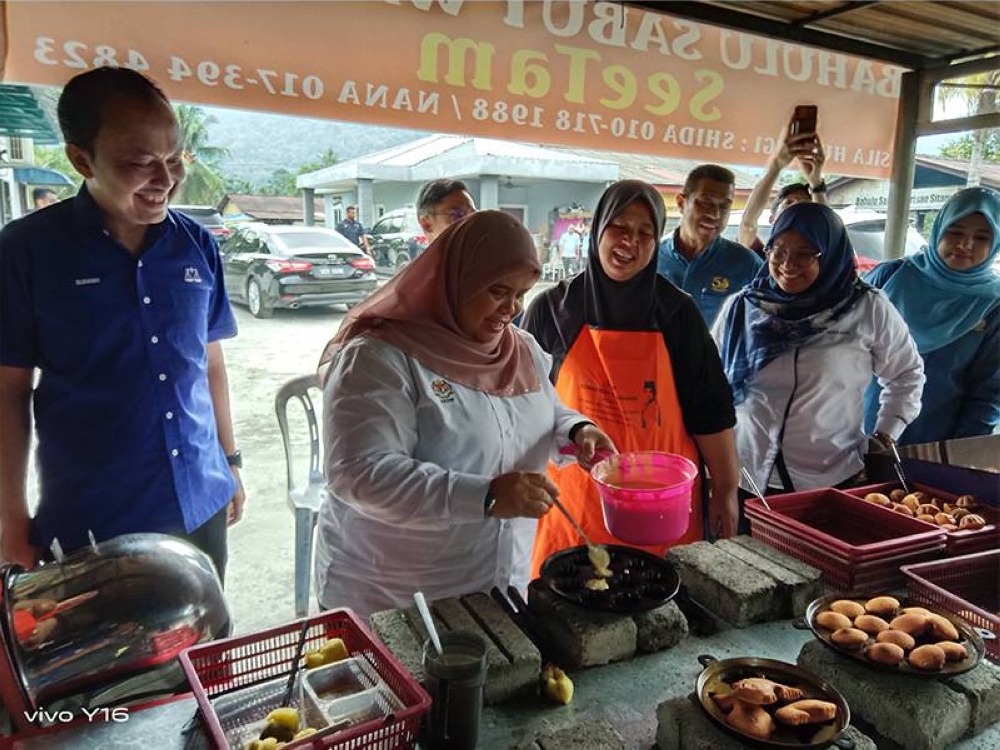 Rubiah (tiga kiri) meletakkan adunan bahulu yang diusahakan Hamsyinar (empat kiri) di bengkel bahulunya di Gadong,Rembau, Selasa lalu.