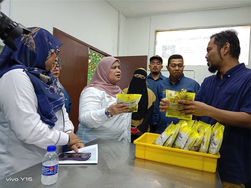 Rubiah (dua kiri) ketika mendengar penerangan berkenaan produk makanan salai yang diusahakan Mohd Khairul (kanan) di Rembau, Selasa lalu.
