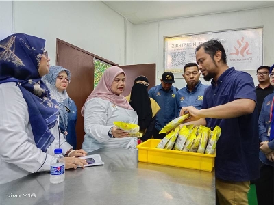 Rubiah (dua kiri) ketika mendengar penerangan berkenaan produk makanan salai yang diusahakan Mohd Khairul (kanan) di Rembau, Selasa lalu.