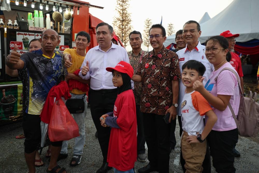 Anthony (tiga, kiri) menyantuni masyarakat setempat di Pulau Warisan pada Khamis. - Foto Bernama