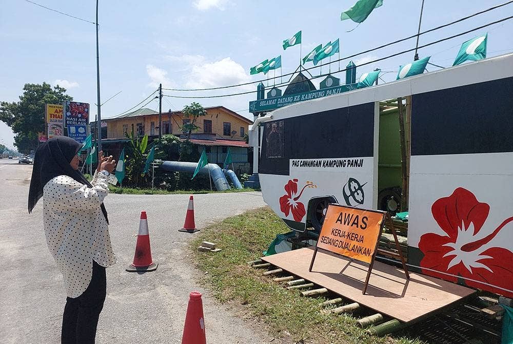 Salah seorang pengunjung mengambil gambar replika bas dua alam di sekitar Wakaf Mempelam di sini pada Jumaat