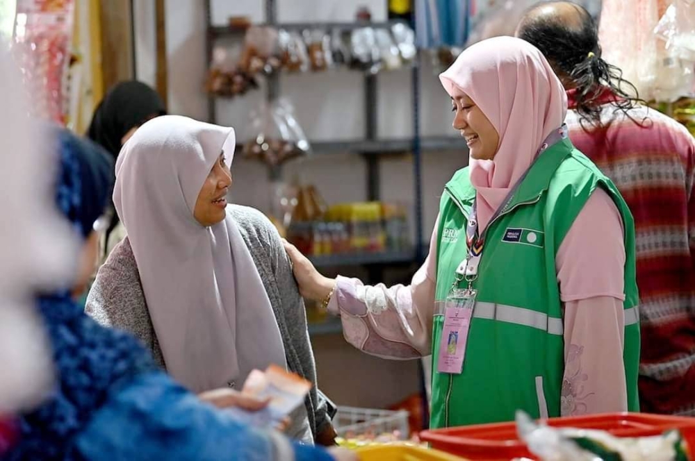 Zuraida (kanan) ketika bertemu peniaga-peniaga dan pengunjung Pasar Bukit Besar dalam program 'Hit and Run: Sis turun mengundi' anjuran Pas DUN Ladang.