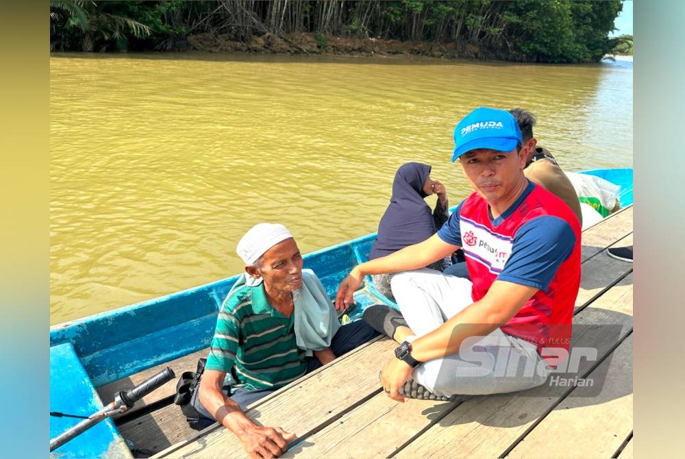 Mohd Rosdi (kanan) menyapa penduduk pulau yang berada di atas bot di Jeti Pangkalan Che Lat.