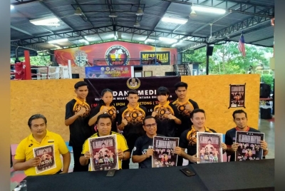 Zainol Fadzi (duduk, tengah) menunjukkan poster kejohanan yang akan mempertemukan atlet muay thai dari dua negara, Malaysia dan Thailand pada 26 Ogos depan di Ipoh.