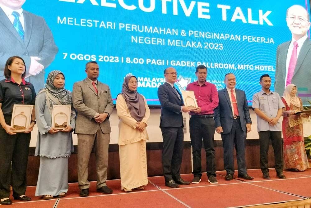 Hee Sem menyerahkan sijil perakuan kepada wakil majikan ketika penutupan program Pendidikan Perburuhan2023: Melestari Perumahan dan Penginapan Pekerja Negeri Melaka di Ayer Keroh pada Isnin.