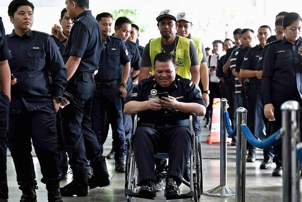Petugas Suruhanjaya Pilihan Raya (SPR) membantu dan memudahkan pergerakan anggota polis yang berkerusi roda akibat masalah kesihatan bersemangat hadir untuk manunaikan tanggungjwabnya sebagai pengundi awal sempena Pilihan Raya Negeri Selangor di Dewan D'Cerana, Ibu Pejabat Polis Kontinjen Selangor hari ini.