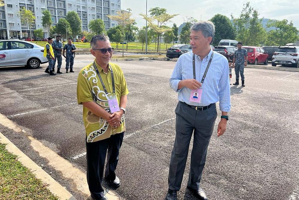 Mohamad (kanan) dan Rozmal (kiri) bertemu di pusat pengundian awal di Pengkalan Udara Sendayan pada Selasa.