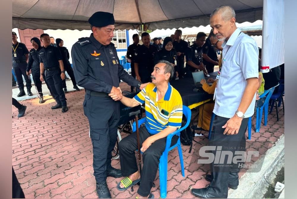Ketua Polis Kelantan, Datuk Muhamad Zaki Harun (kiri) bersalam dengan Che Mustapa (tengah) ketika bertemu di pusat pengundian Taska di IPK Kelantan.