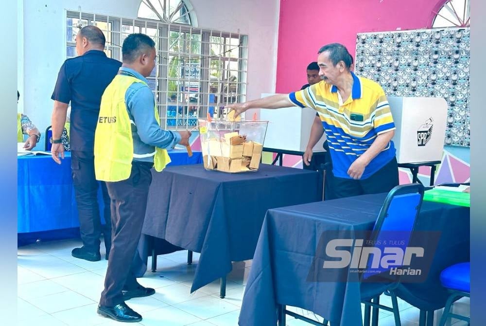 Che Mustapa Che Ahmad (kanan) selesai membuang undi awal bagi PRN pada Selasa.