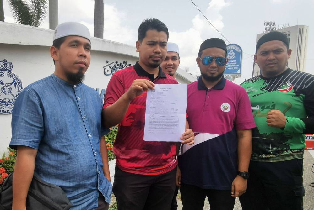 Mohd Hilmi (dua dari kiri) menunjukkan salinan laporan polis yang dibuat di IPD Kuala Terengganu pada Selasa.