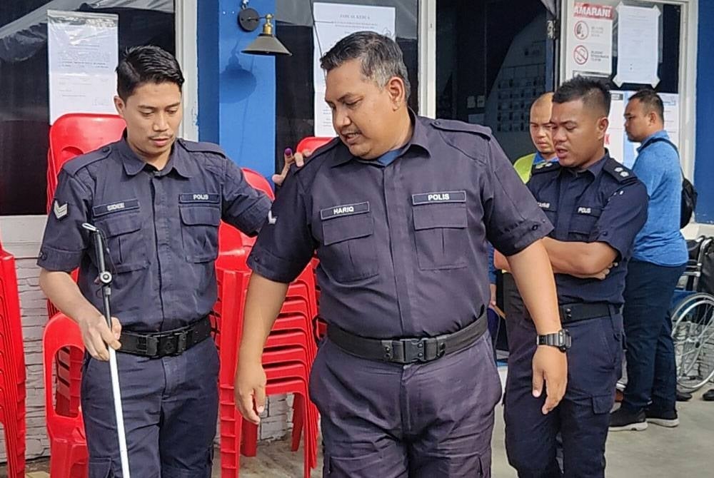 Abdullah Sidee (kiri) dipimpin rakannya ketika mengundi awal di IPD Kuala Selangor pada Selasa.