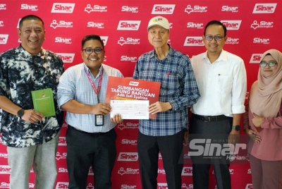 Lam Thye (tengah) menyerahkan cek sumbangan kepada Ketua Pengarang Sinar Harian, Zamri Rambli di Kompleks Karangkraf pada Selasa.