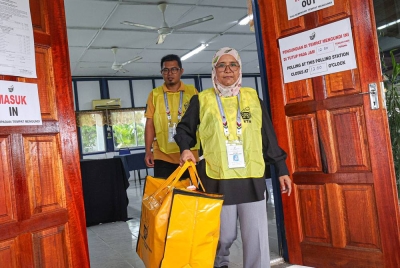 Petugas SPR membawa keluar peti undi selepas pusat pengundian di Bilik Maklumat Balai Polis Kerteh ditutup tepat pada 12 tengah hari. - Foto Bernama