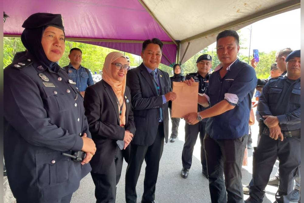 Jeffridin (kanan) menyampaikan memorandum kepada wakil kerajaan negeri di pekarangan Menara Kinabalu, Kota Kinabalu.