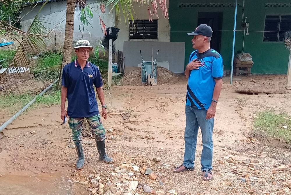 Ahmad Hasbullah dan Azman menunjukkan sistem perparitan yang cetek dipenuhi tanah kesan banjir lumpur sejak setahun lalu.