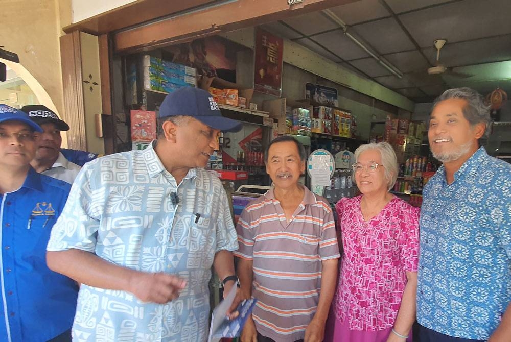 Khairy (kanan) dan Reezal (dua dari kiri) ketika turun berkempen di Pekan Lama Kepala Batas, pada Khamis.