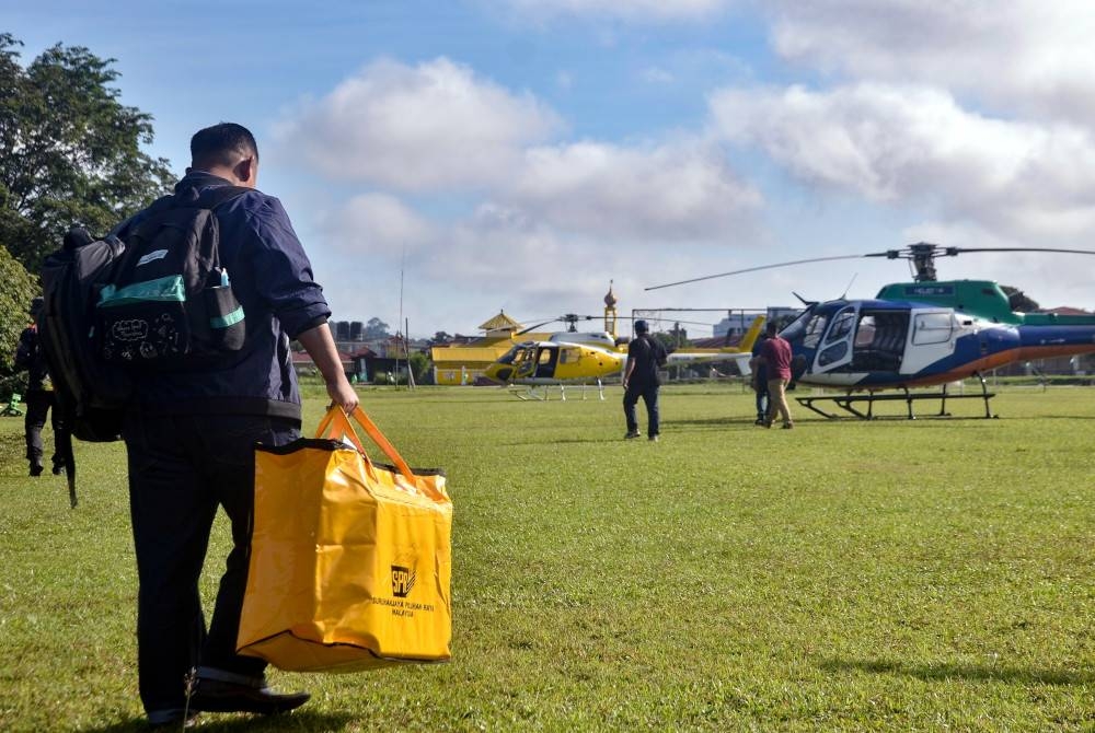 Petugas SPR membawa peti undi untuk dihantar ke pusat mengundi di penempatan Orang Asli bagi DUN Galas dan DUN Nenggiri di Padang Kompleks Serbaguna Majlis Daerah Gua Musang, hari ini. - Foto Bernama