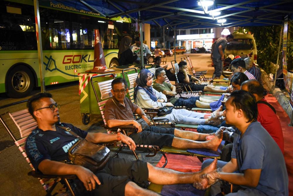 Sebahagian orang ramai yang mendapatkan khidmat urut di tepi jalan yang diusahakan Sulaiman di tengah ibu kota. FOTO: MOHD RAFIQ REDZUAN HAMZAH