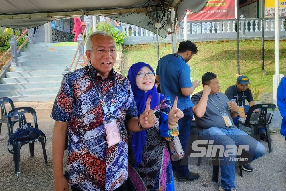 Mahdzir bersama isteri menunjukkan jari yang dicelup dakwat sebagai bukti sudah melaksanakan kewajipan mengundi.