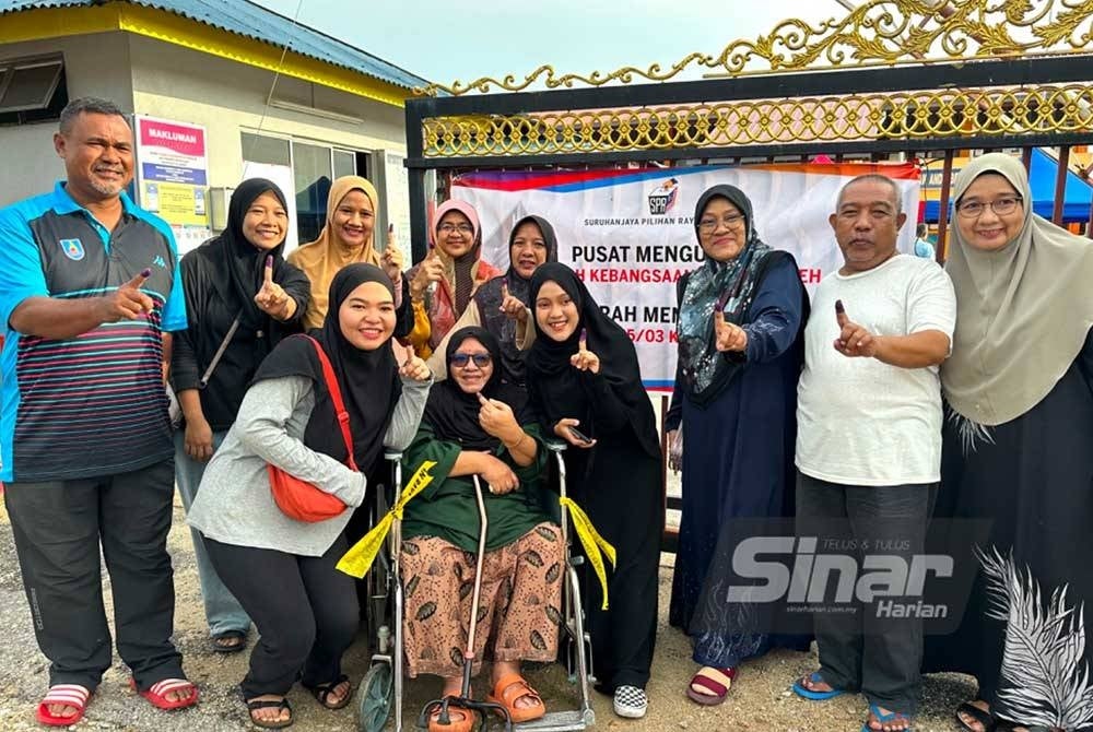 Aminah (tengah) berkerusi roda bersama ahli keluarganya yang membuang undi di Ketereh, Kota Bharu pada Sabtu.