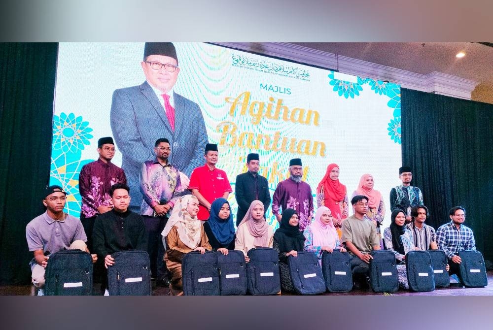 Asmadi (tengah) bersama 16 anak kepada asnaf penerima bantuan bulanan yang melanjutkan pembelajaran ke institut pengajian tinggi diberikan sumbangan komputer riba pada majlis penyerahan bantuan pendidikan dan pembangunan asnaf miskin di Hotel Grand Makmur di sini pada Sabtu.