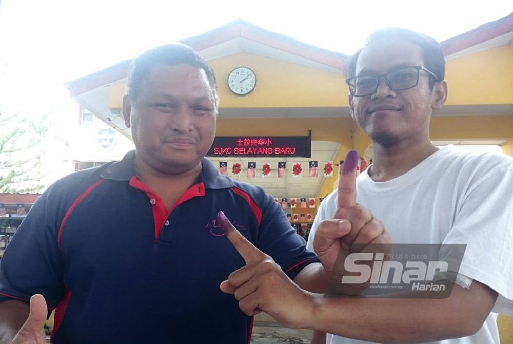 Muhamad Zamri (kiri) bersama anak selesai membuang undi di SJK (C) Selayang Baru pada Sabtu.