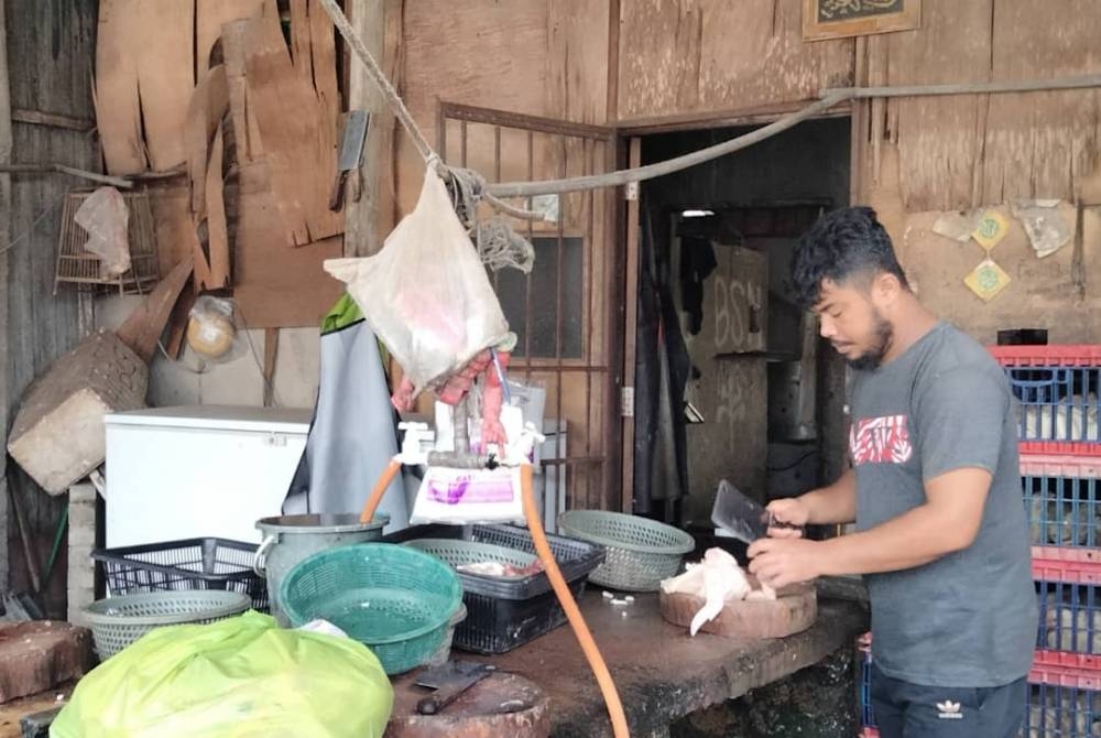 Danial memotong ayam yang dipesan pelanggan.