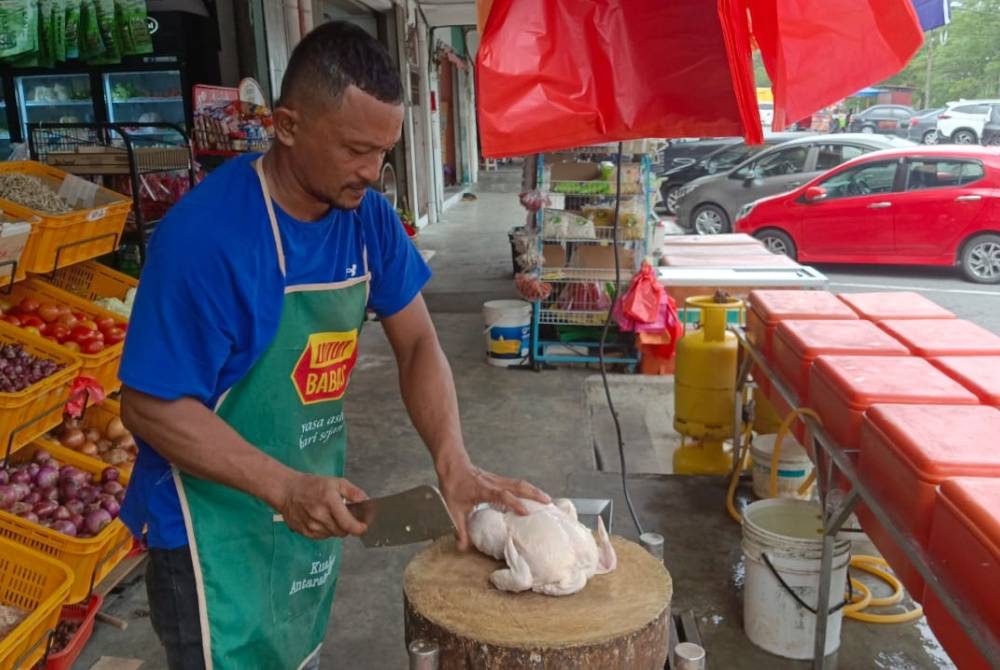 Shafie memotong ayam yang dijual pada harga RM8.70 sekilogram di pekan Kota Masai, Pasir Gudang, pada Isnin.