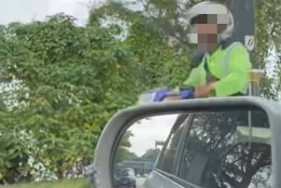 Tangkap layar video tular menunjukkan pekerja pembersihan yang bertindak membuang sampah di Pantai Lido.