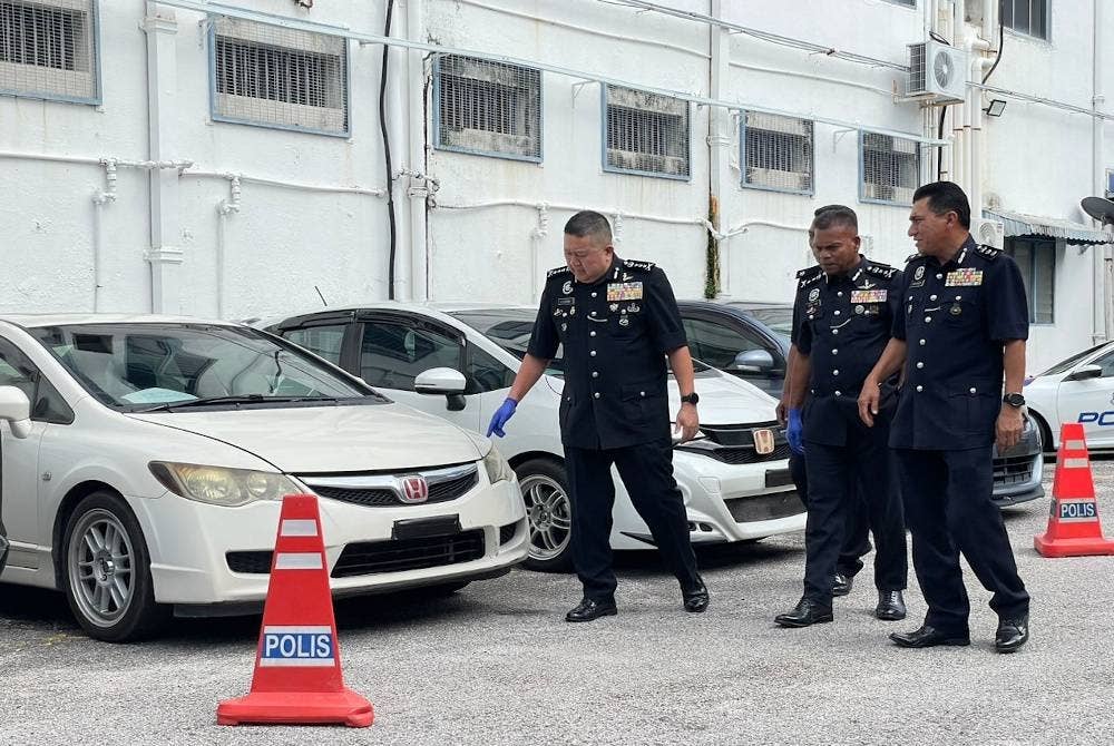 Kok Chin (kiri) memeriksa kenderaan yang dirampas daripada suspek.