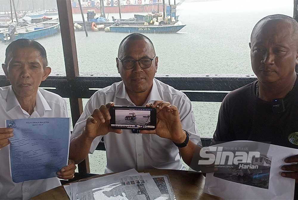 Pandak (tengah) dan Faizan (kanan) menunjukkan laporan polis dan gambar jaring nelayan tempatan yang didakwa dilanggar bot penguat kuasa Singapura.