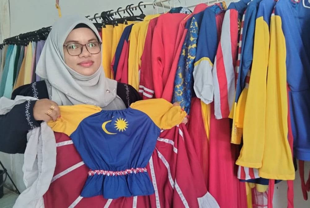 Marhaini menunjukkan gaun kanak-kanak bertema kemerdekaan yang menjadi pilihan pelanggan.