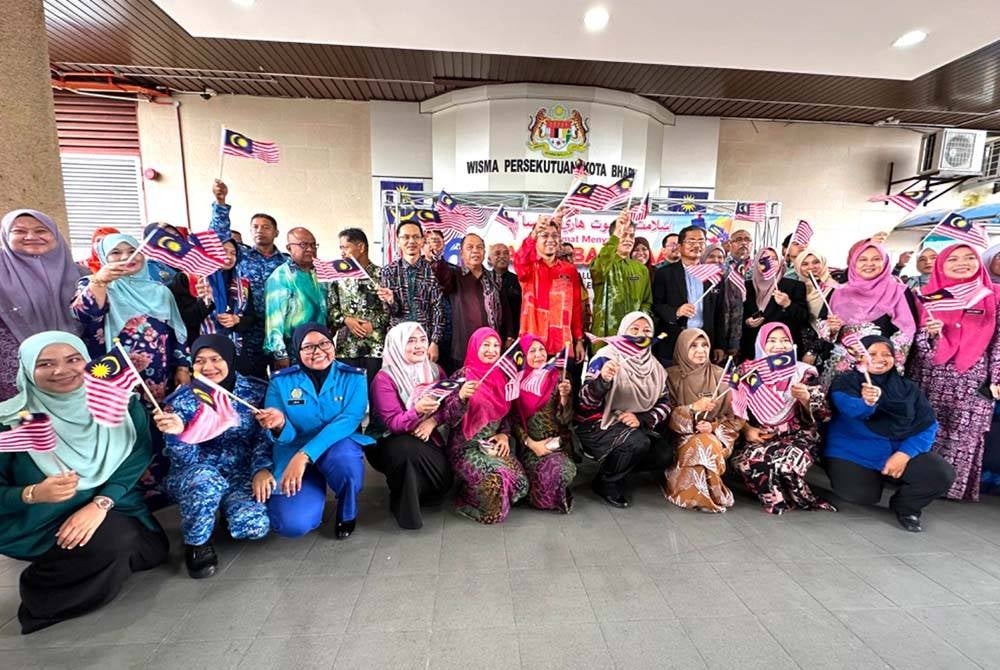 Kakitangan wisma bersama Muhd Nor Aswadi (tengah) mengibar bendera sempena Sambutan Jalur Gemilang Peringkat Wisma Persekutuan negeri Kelantan.