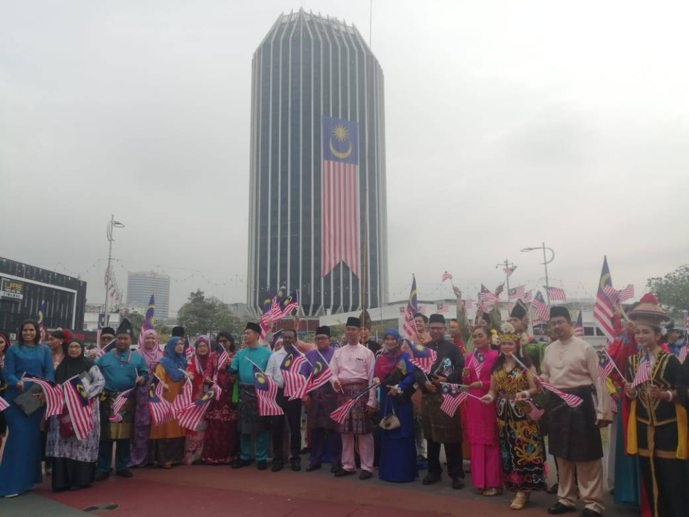 Warga MBPJ bergambar berlatar belakang Jalur Gemilang gergasi yang dipasang di bangunan MBPJ sempena Bulan Kemerdekaan.