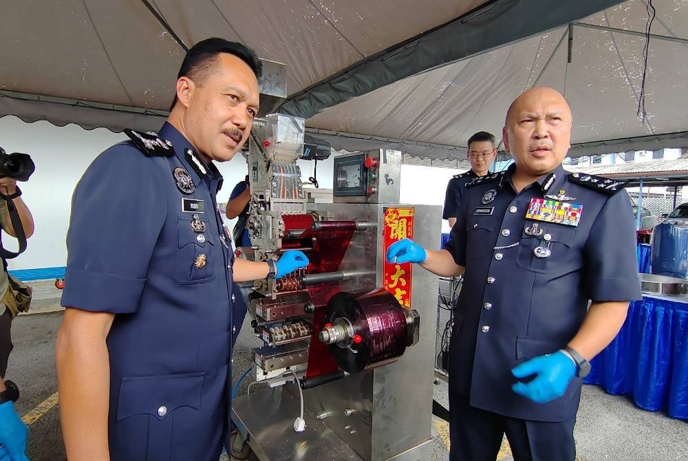 Mohd Kamarudin (kanan) bersama Ketua Polis Perak, Datuk Seri Mohd Yusri Hassan Basri menunjukkan mesin membungkus dadah jenis erimin 5 di Ipoh.