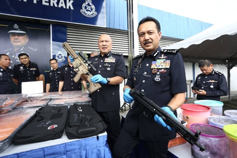 Mohd Kamarudin dan Ketua Polis Perak, Datuk Seri Mohd Yusri Hassan Basri (kanan) menunjukkan dua senjata api tiruan yang dirampas daripada suspek.