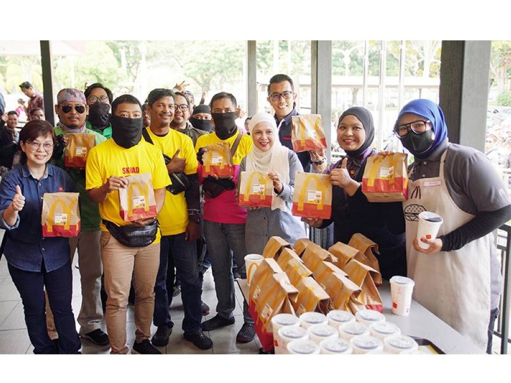 Melati (tiga dari kanan) dan Felina (kiri) bersama penunggang penghantaran menunjukkan isyarat bagus pada program Mekdi Belanja Rider yang diadakan di restoran McDonald's, Putrajaya pada Khamis. 