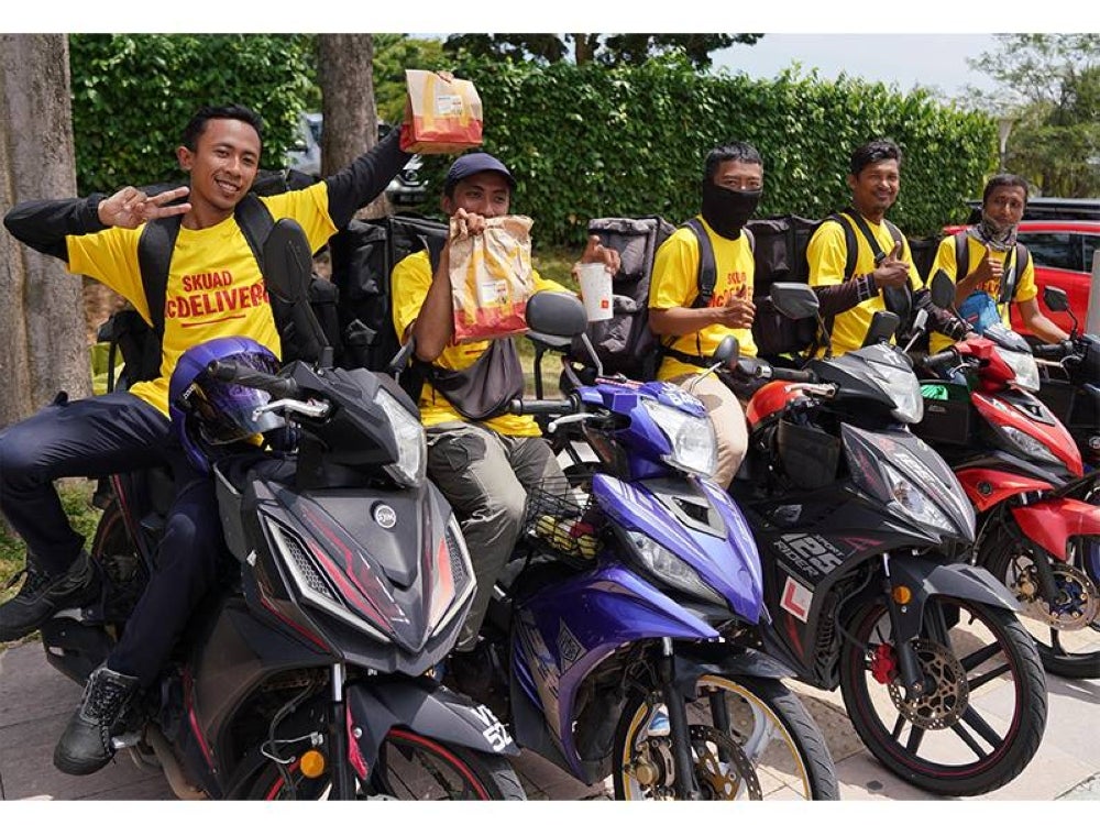 Antara ‘riders’ yang gembira sambil menunjukkan hidangan yang diterima mereka semasa program Mekdi Belanja Rider di Putrajaya pada Khamis.