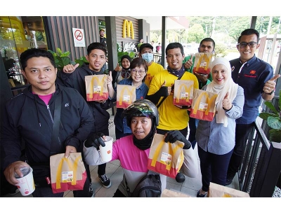 Melati (dua dari kanan) dan Felina (tengah) bergambar bersama ‘riders’ pada program Mekdi Belanja Rider di restoran McDonald’s, Putrajaya pada Khamis. 